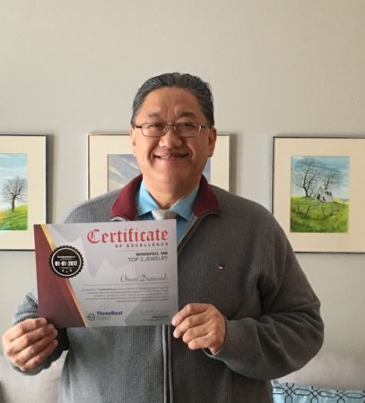 Jim Omori displaying our award for being in the top 3 best rated jewellers in Winnipeg.